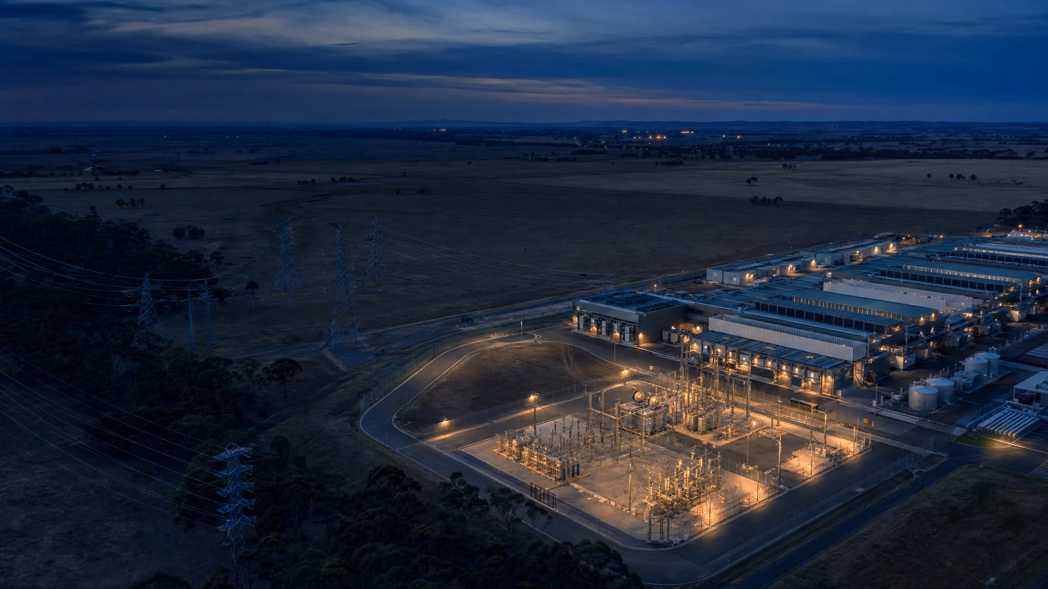 Australian data centre campus beside high-voltage infrastructure at dusk